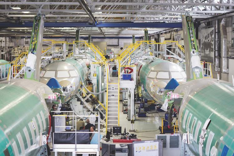 Several large jet airliners being built in manufacturing plant using high bay lighting